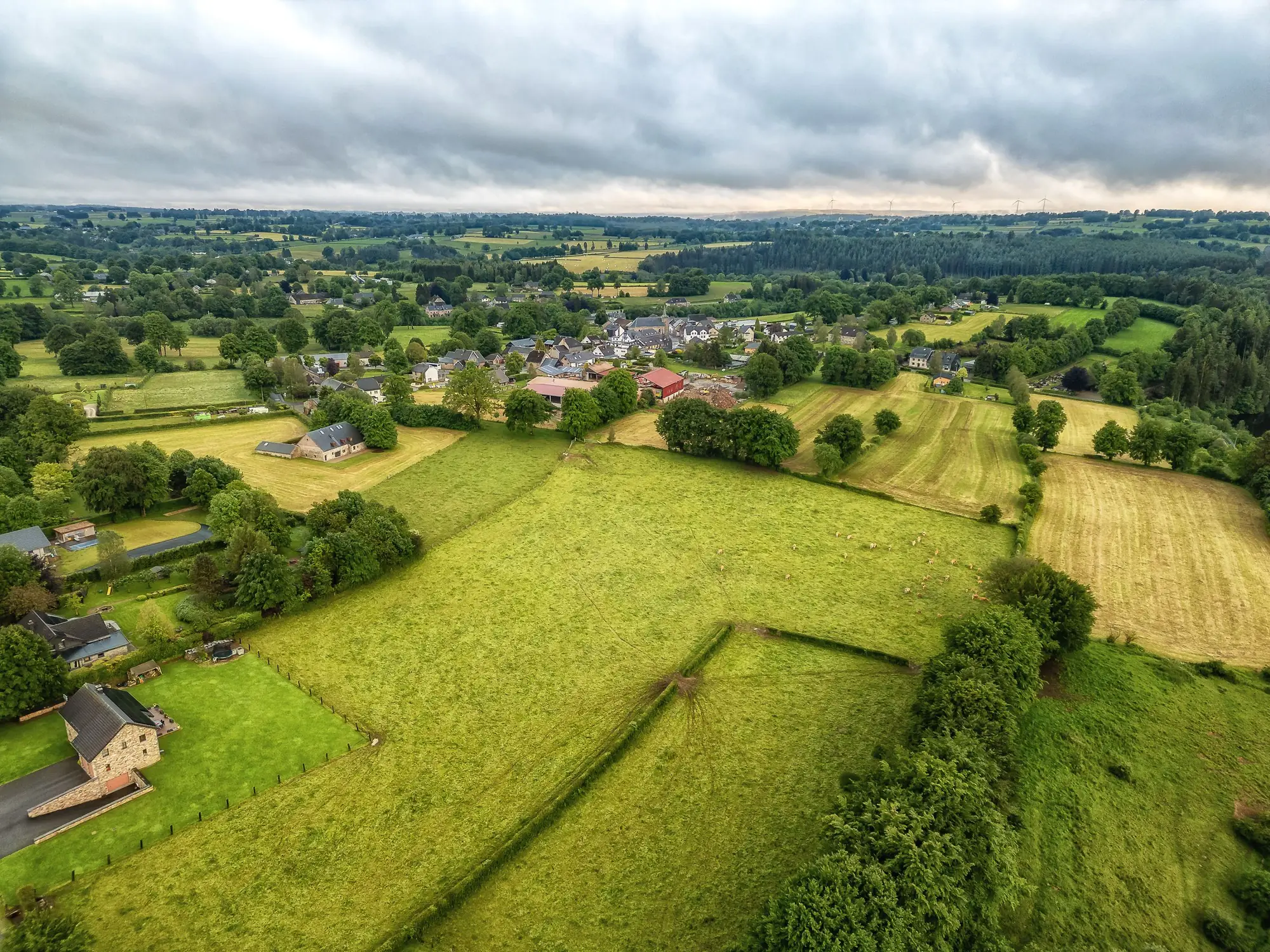 Glooiende weiden en een dorp op het Belgische platteland